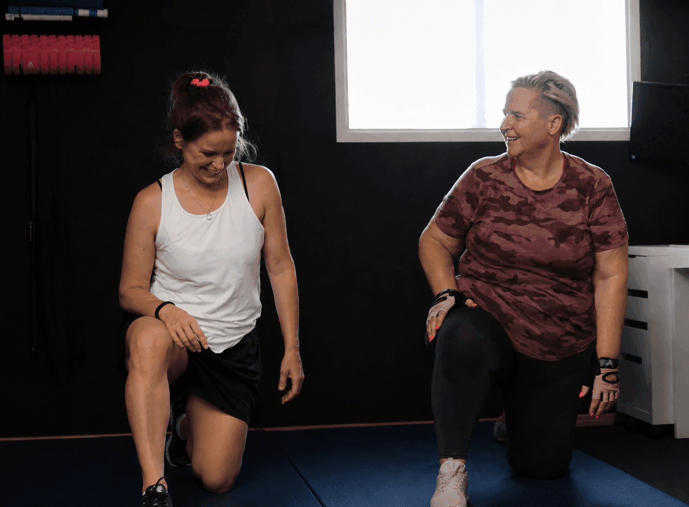 Esther and a client doing lunges together, laughing, in the private Worthing studio
