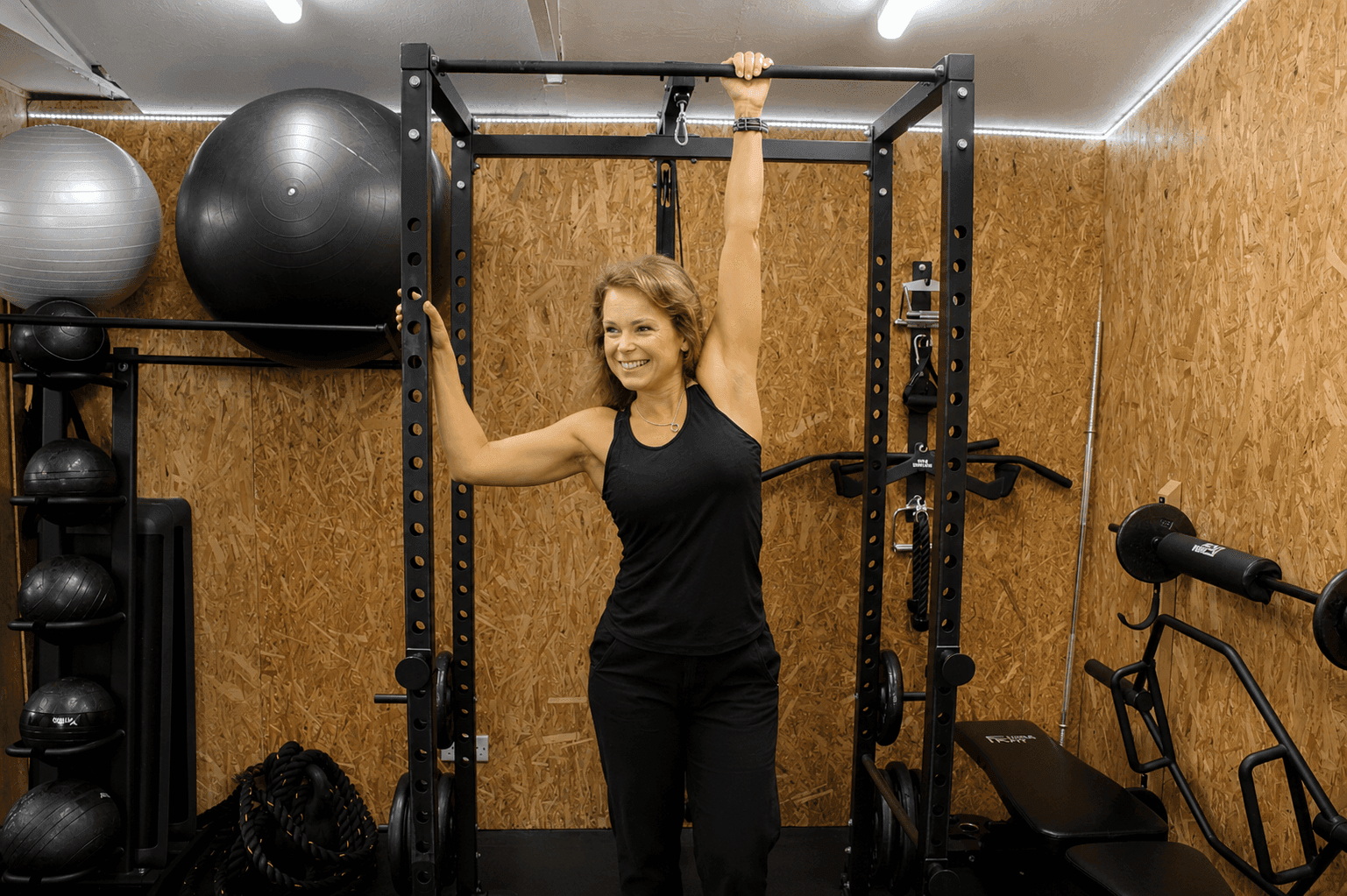 Esther Fair smiling mid-stretch at the power rack in her private Worthing studio