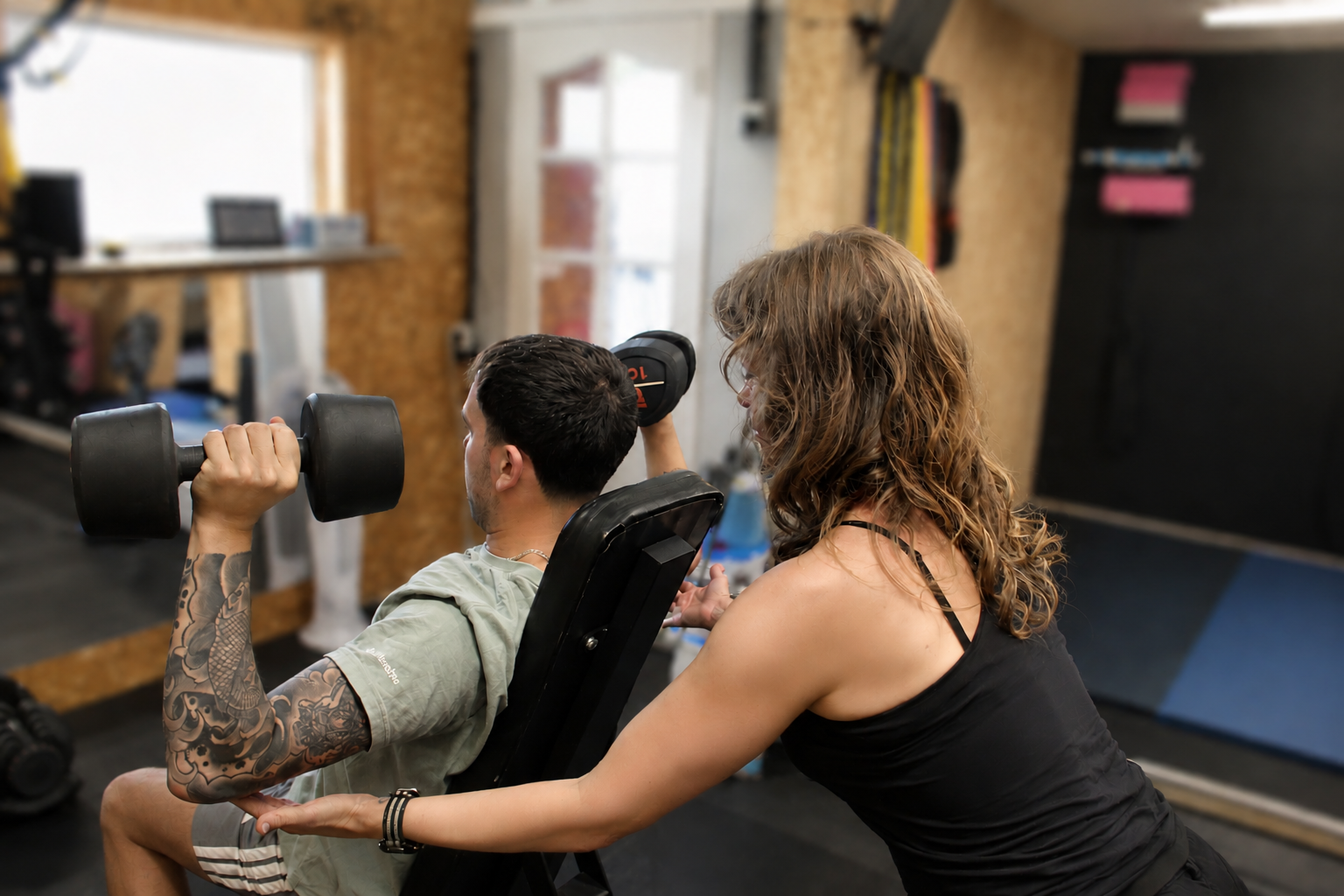 Esther coaching a client through a dumbbell exercise in the studio