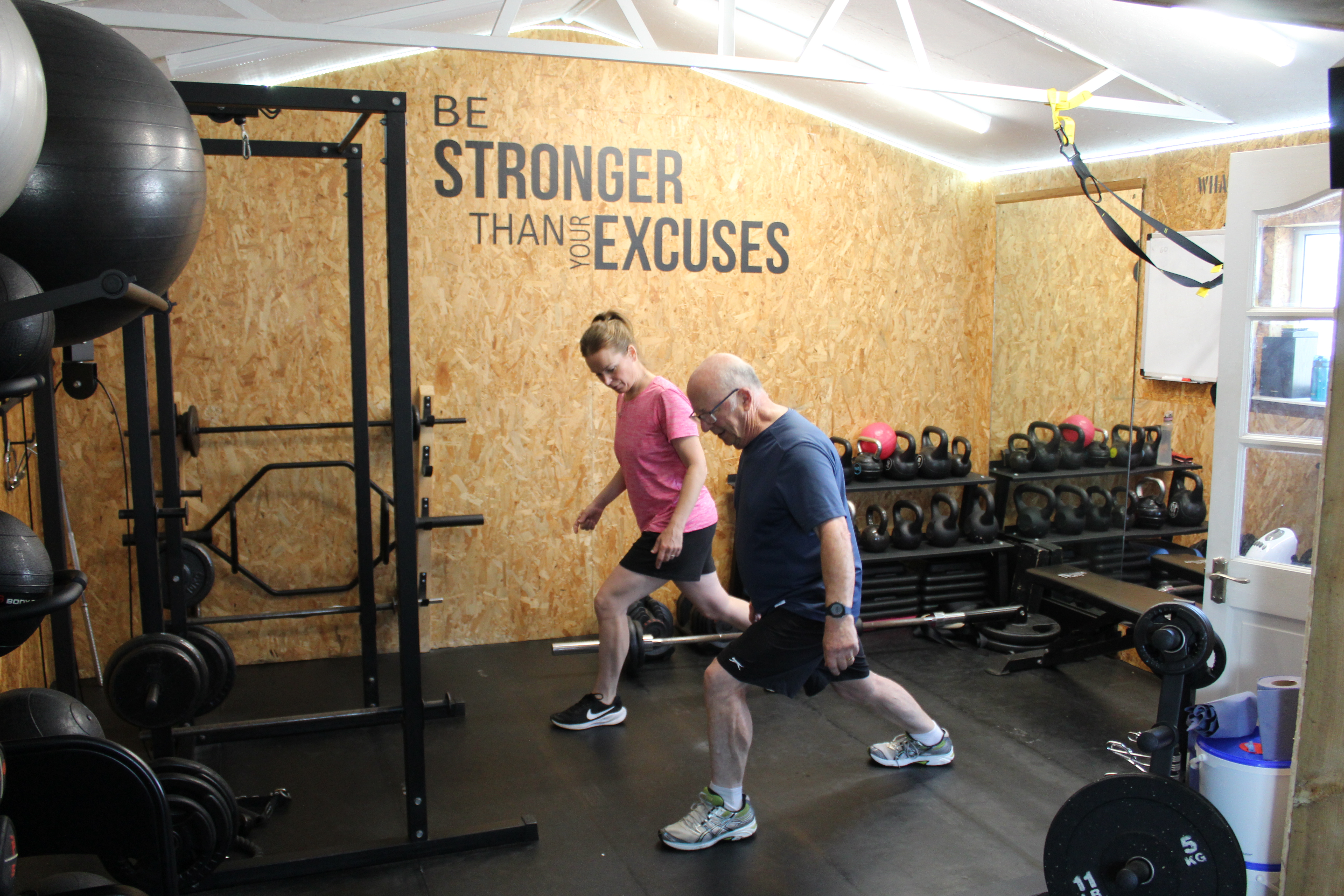 Esther coaching a client through a walking barbell lunge in the private Worthing studio